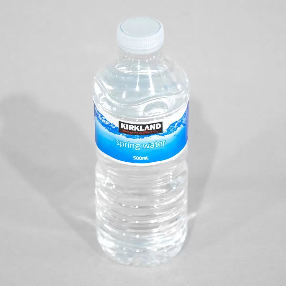 Kirkland Signature 500ml bottle of spring water with a blue label and white cap, placed on a plain background.